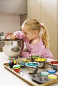 Girl stirring cupcake mixture, decorating ingredients