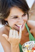 Young woman eating muesli with fresh fruit