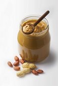 A jar of peanut butter with fresh peanuts