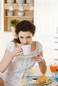Junge Frau trinkt Kaffee am Frühstückstisch