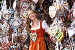 Woman in dirndl by stall selling Lebkuchen hearts (Oktoberfest)
