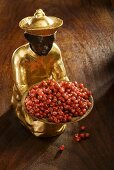 Gilded statuette with a bowl of red pepper