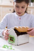 Mädchen macht Lebkuchenhaus zu Weihnachten