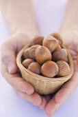 Hands holding a basket of hazelnuts