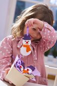 Mädchen hält Schneemann-Baumanhänger aus Salzteig