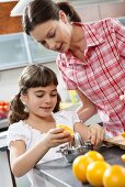 Mother and daughter squeezing oranges in a kitchen