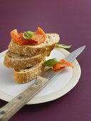 Three slices of baguette with smoked salmon and basil