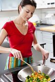 Woman frying vegetables in wok frying pan