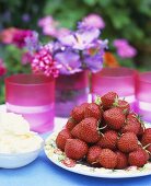 Frische Erdbeeren und Schalgsahne auf einem Gartentisch