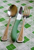 Knife, fork and spoon on checked tablecloth