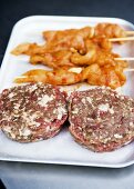 Raw burgers and chicken shish kebabs ready for grilling