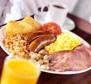 Englisches Frühstück mit Würstchen, Speck, Rührei und Gemüse