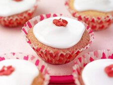 Cupcakes mit weisser Glasur und roter Zuckerblüte