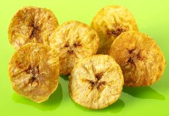 Banana chips on green background