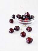 Cherries in a glass bowl and scattered around the table