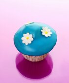 Muffin with blue icing and sugar flowers