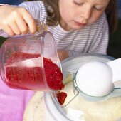 Little girl pouring fruit into ice cream maker
