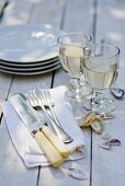 Glasses of white wine, cutlery and plates on wooden table
