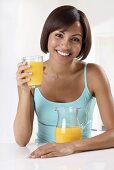 A woman holding a glass of orange juice
