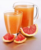 Pink grapefruit juice in a glass and a glass jug