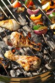 Chicken legs and vegetable kebabs on a barbeque