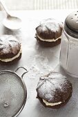 Three chocolate whoopie pies, icing sugar and a sieve