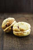 Cranberry-Orangen-Whoopie Pies, gefüllt mit Orangen-Vanille-Creme auf Holzuntergrund