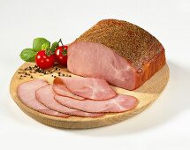 Sliced pepper ham on a wooden plate