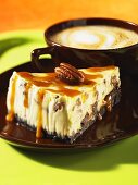 A slice of caramel cheesecake with pecan nuts and a cafe latte