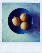 Three lemons in a blue bowl