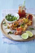 Skewers with ham cubes, pineapples and sweet chili sauce