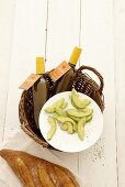 Slices of avocado on a plate with bottle of salad dressing and white bread
