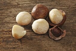 Macadamia nuts, with and without shells on a wooden surface