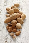 Almonds with and without shells on a white wooden surface