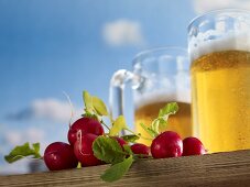Tankards of beer and radishes against a blue sky