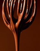Melted chocolate running off a whisk (close-up)