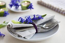A place setting with a napkin, cutlery and hyacinths