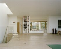 A modern, open plan living room with a parquet floor, chairs in front of a glass balustrade and a built in bookshelf