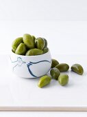 Green olives in a bowl and next to it