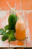 Gurkensmoothie und Melonensmoothie in Flaschen mit Strohhalmen