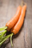 Three carrots on a wooden surface