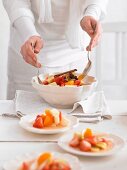 A woman serving fruit salad