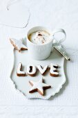 A cinnamon star and letters with a cup of cappuccino
