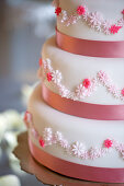 A three tier wedding cake in pink and white