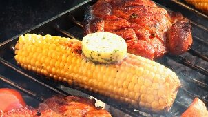 Corn on the cob with herb butter & pork neck steaks on barbecue