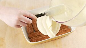 Preparing tiramisu: covering the espresso-soaked sponge fingers with mascarpone cream