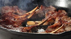 Lamb chops being fried in a pan