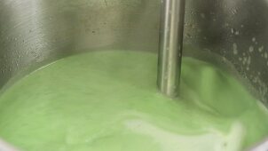 Pea soup being pureed with a hand blender