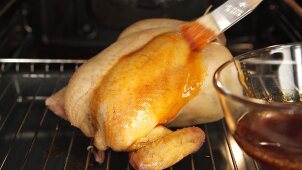 Roast chicken being brushed with spiced butter