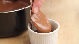 Chocolate souffle being poured into a prepared ramekin